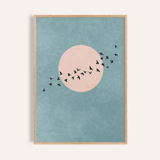 Framed close-up of wall art birds with a pink sun and black birds on blue background