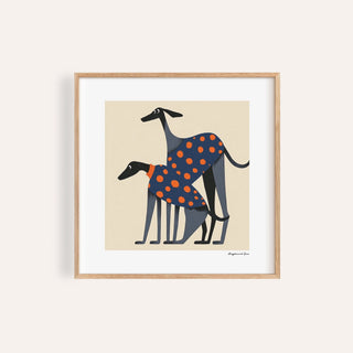 Framed print close-up of two greyhounds in orange polka dot coats on cream background
