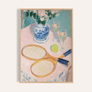 Framed print of tennis rackets with a ball and wine glasses on a pink tablecloth
