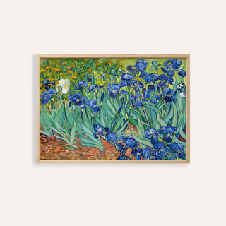 Blue iris wall art of blue and white flowers with green leaves in a light wood frame