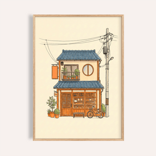 Framed print of a Japanese style art print showing a small bakery house in warm colours with a blue roof and a bicycle