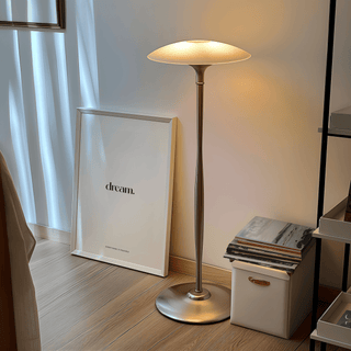 Print leaning on the floor showing a minimalist dream quote poster with white frame beside a silver lamp and magazines