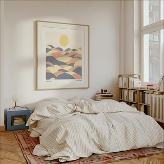 Pastel wall art of abstract hills with sun in soft yellow pink and blue above a bedside table lamp