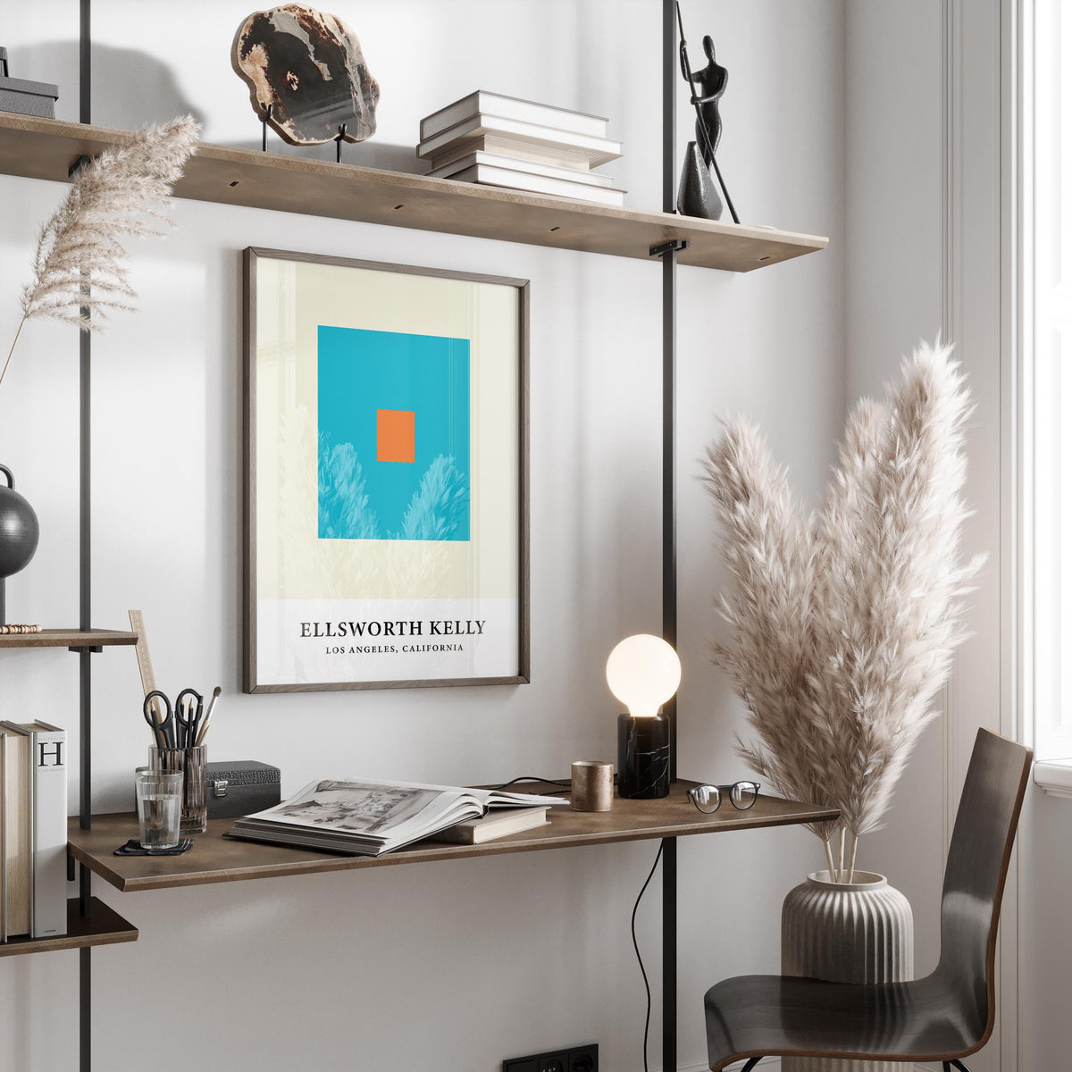 Wall office art with orange and blue squares framed above a tidy desk with books and a lamp