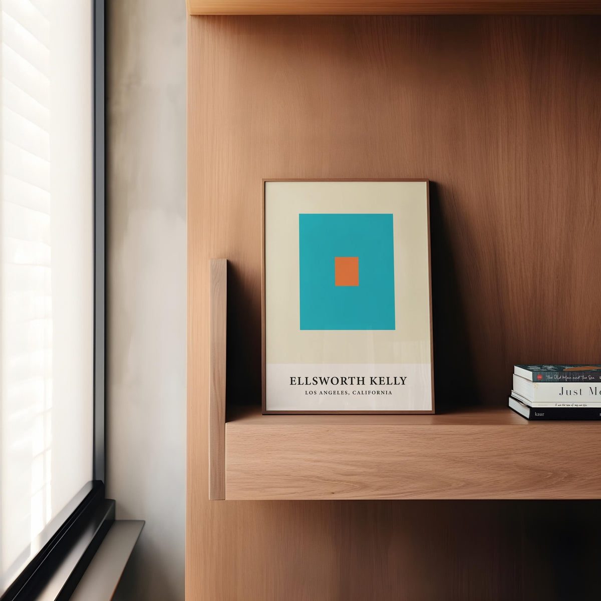 Print leaning on a shelf with orange and blue squares in a room with wooden walls and books nearby