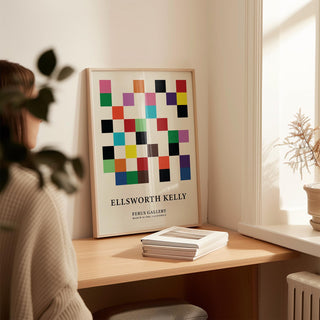 Posters for Office print with colorful squares leaning on a wooden desk with books nearby in soft daylight