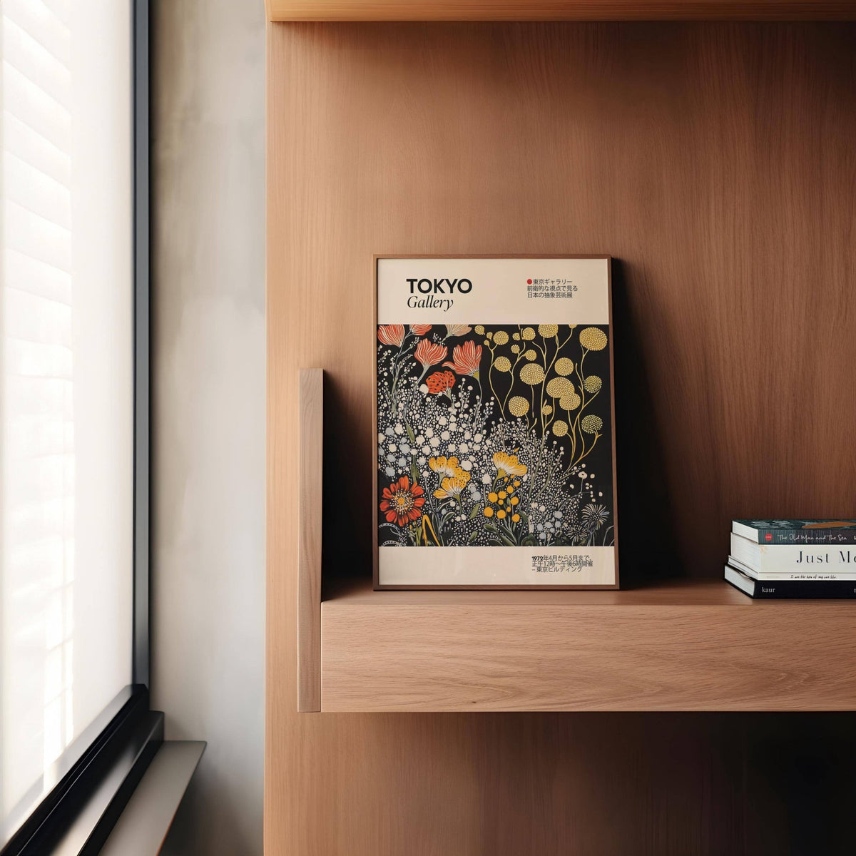 Vintage Japanese wall art print leaning on a wood shelf beside stacked books with stylised flowers in yellow and red