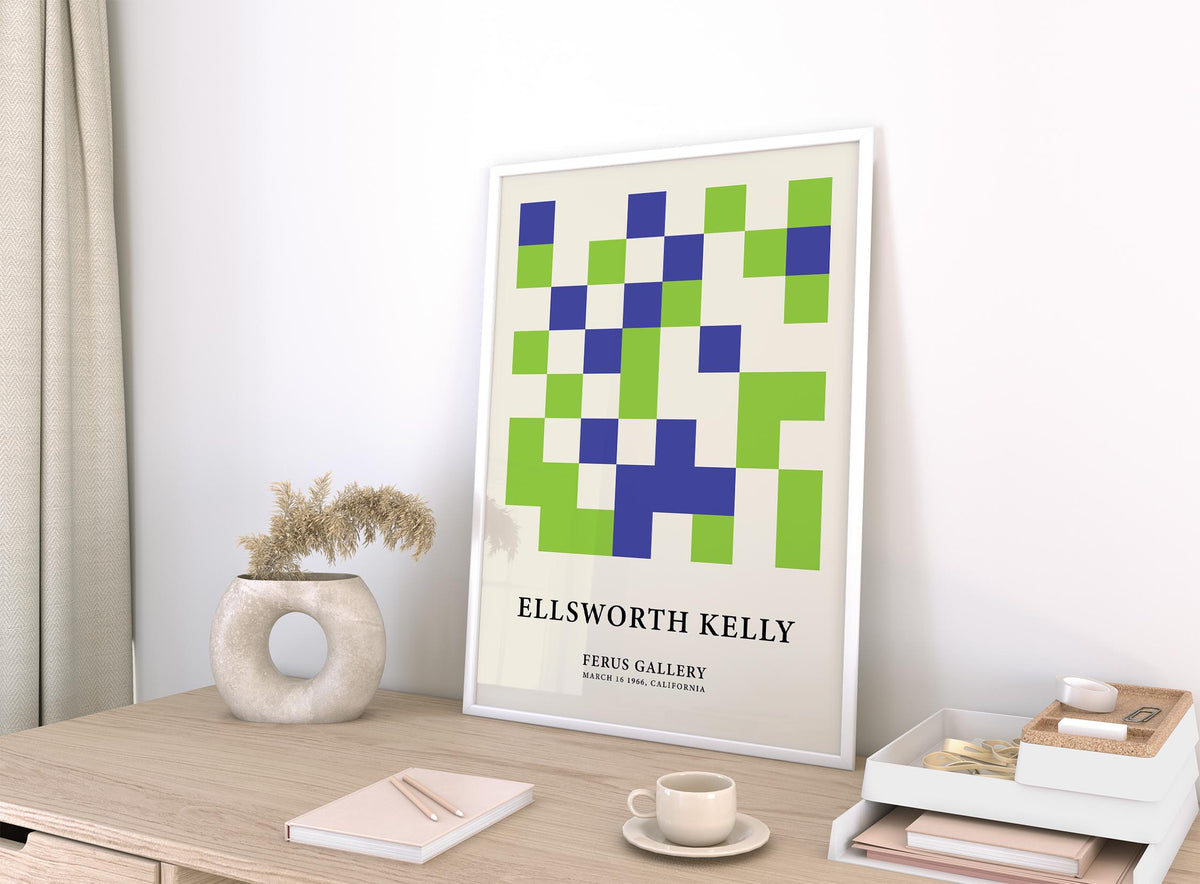 Minimal wall art with green and blue squares leaning on a wooden desk near a beige decorative vase