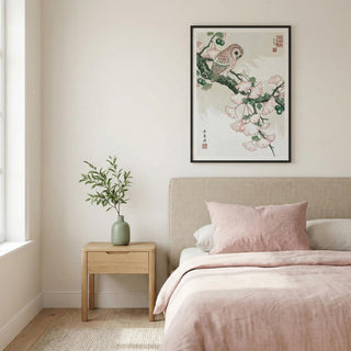 Owl art print in black frame showing an owl perched on a ginkgo branch above a bed with pale pink bedding