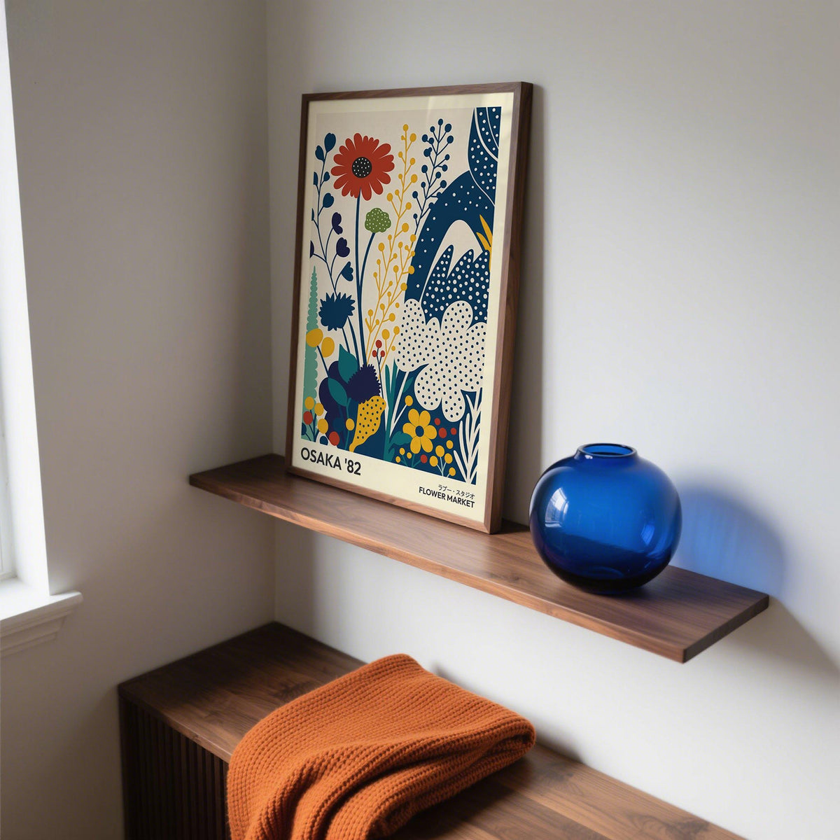 Poster Flowers print with stylised flowers in blue, red and yellow on a wooden shelf with a blue vase