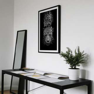 Leopard Photography Print showing two leopards in black and white above a black desk with documents and a plant