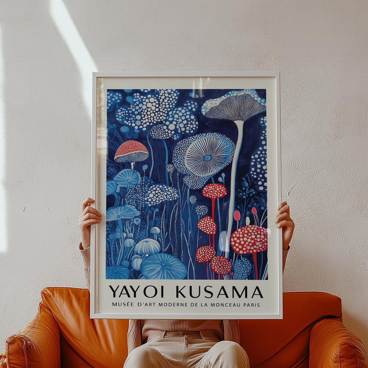 Mushroom print held in hands showing red and blue mushroom illustration with white text