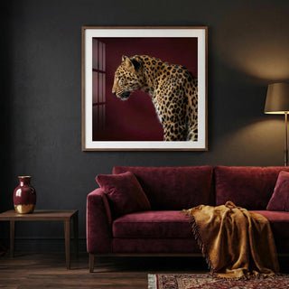 Leopard art print of a side profile leopard with maroon background above a sofa in a lounge