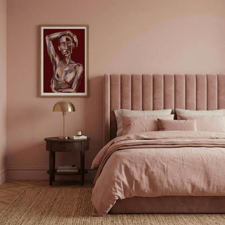 Contemporary Figure Art framed print of an abstract human figure with warm earthy tones above a bedside table in a pink bedroom