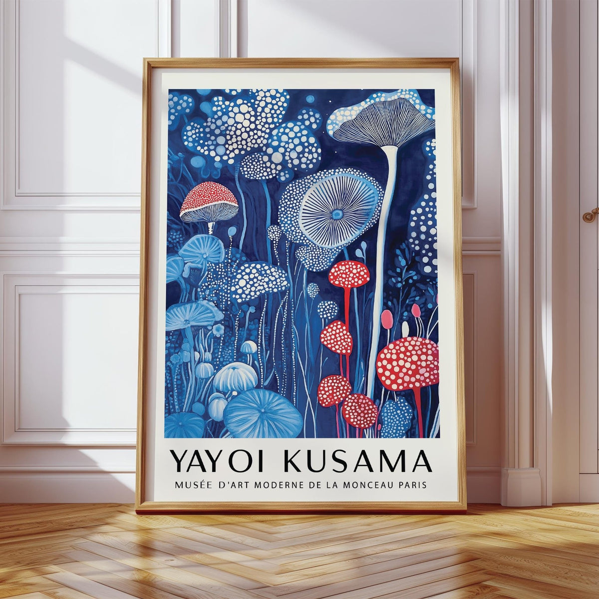 Framed mushroom print with red and blue mushrooms leaning on a wooden floor in a white room