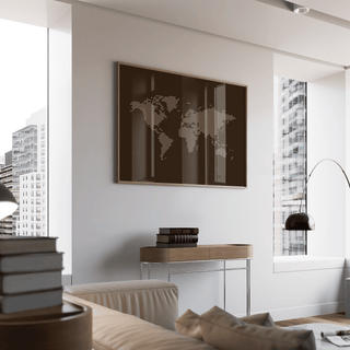 World Map Poster print featuring a minimalist brown map with beige dots hung above a wooden table with books