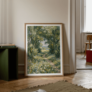 Print leaning on a floor showing a woodland path with green and yellow foliage beside a book stack