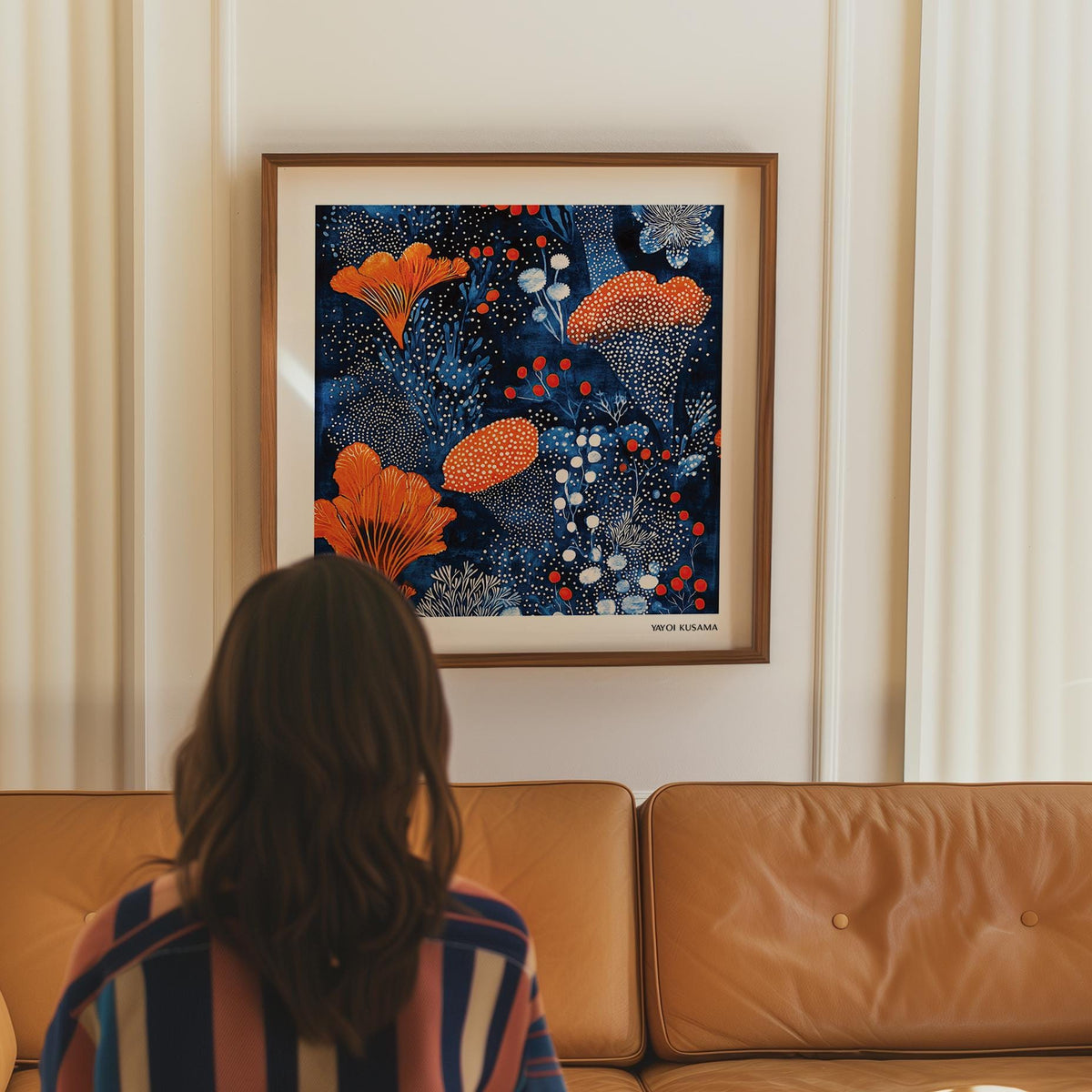 Blue Orange wall art framed print with orange floral pattern above tan leather sofa