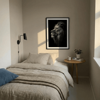 Lion wall art in a black frame with a beige bed and bedside table in a bedroom
