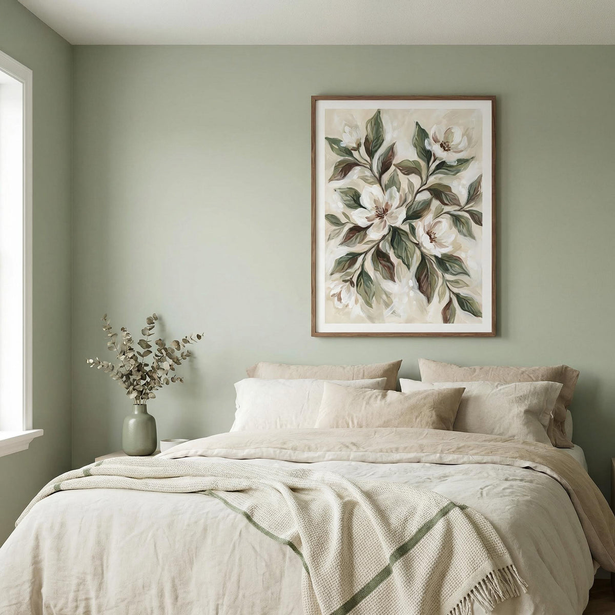 Magnolia wall decor of white magnolia flowers and green leaves above a bed with pillows and blanket