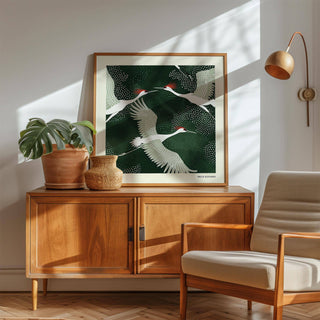White Crane Birds Art print leaning on wooden cabinet with lamp and plant in sunlight