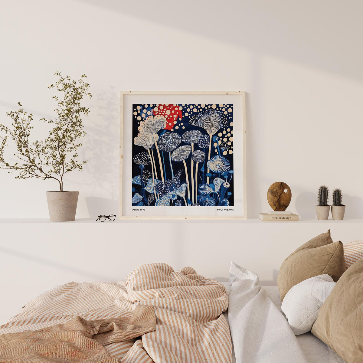 Print on a shelf of red and blue art with abstract mushroom shapes beside a small plant pot