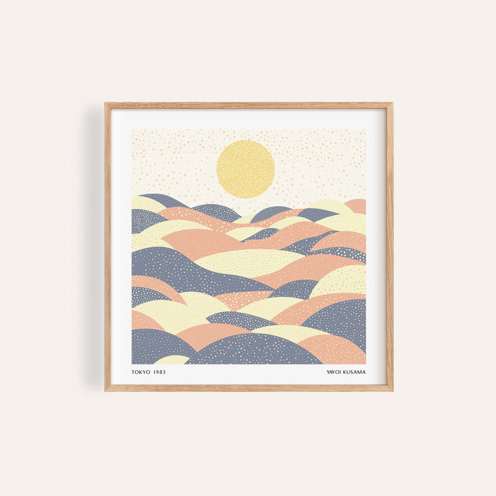 Framed pastel wall art with abstract hills in muted pink and blue tones and a yellow sun