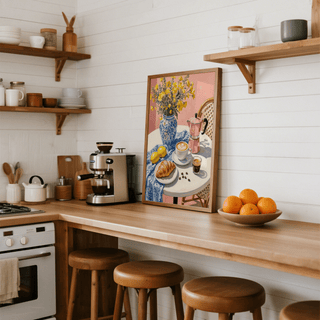 Floral kitchen decor print leaning on a kitchen counter with wooden stools and a bowl of oranges