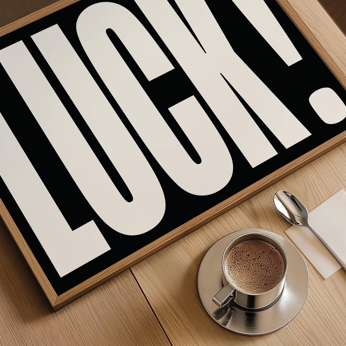 Close-up on lucky gifts wall art with bold white text on black and coffee cup on wooden table