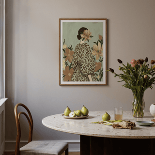 Print on a wall of a woman with a leaf-patterned dress and a flower face above a dining table with fruit and flowers