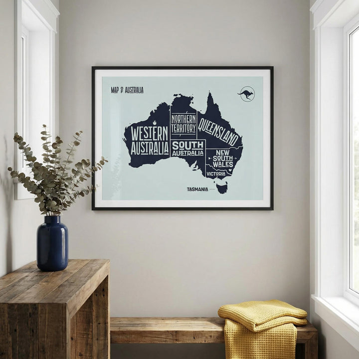 Australia Map Print framed on a wall with a blue vase on a wooden table and yellow blankets nearby