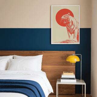 Bold Tiger Wall Art print in minimalist style with red and cream tones above a wooden bed headboard and yellow lamp