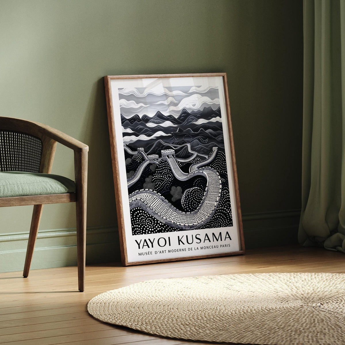 Chinese wall art leaning against a sage green wall near a woven chair and curtain