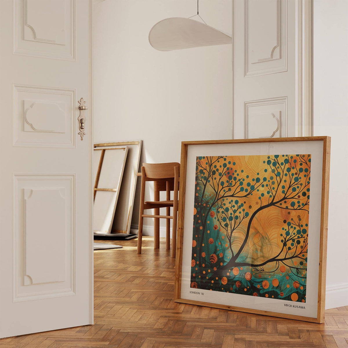 Print leaning on floor of teal and orange abstract tree print with wooden frame in a beige minimal room