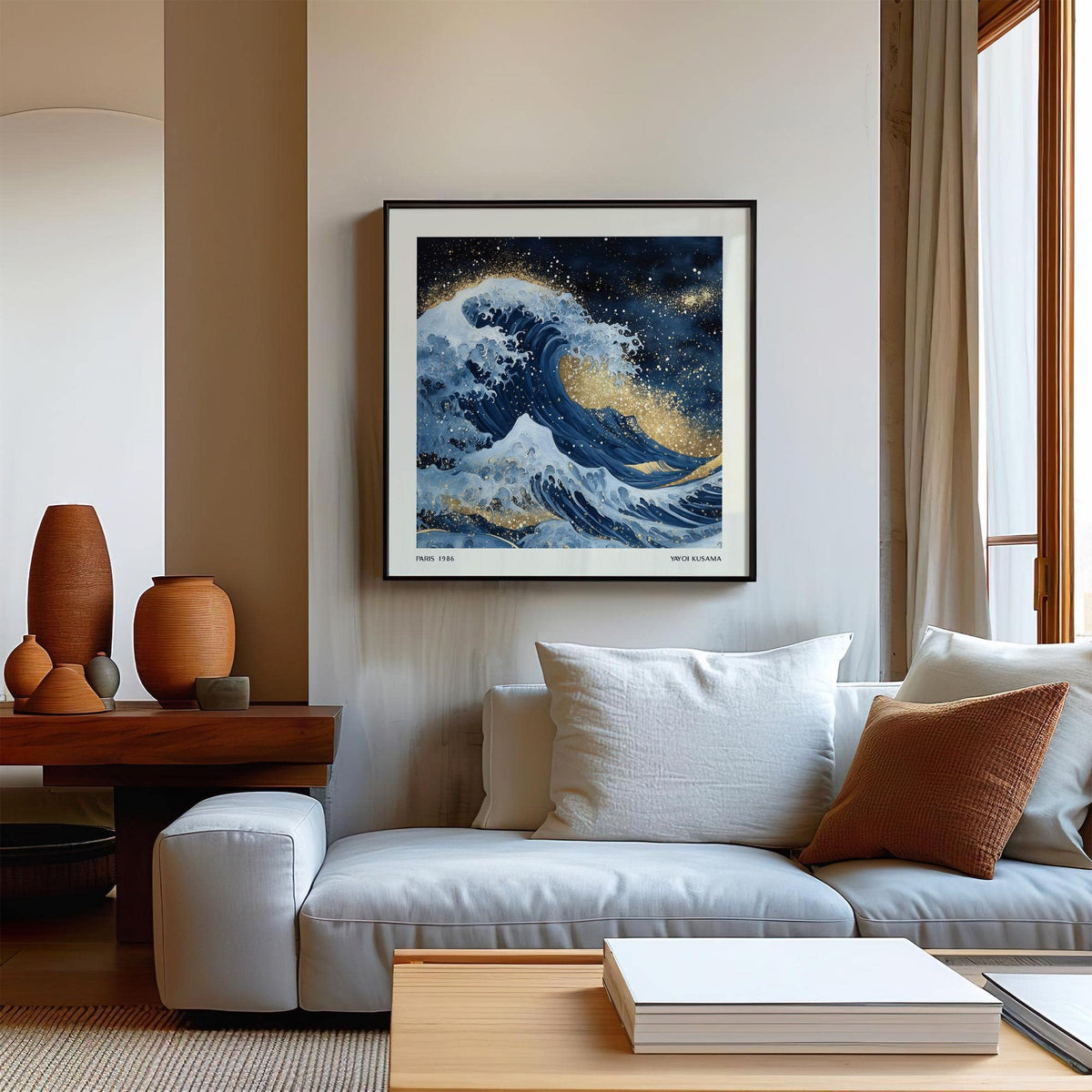 Wall art of the ocean with a blue wave and gold accents above a white sofa in a living room
