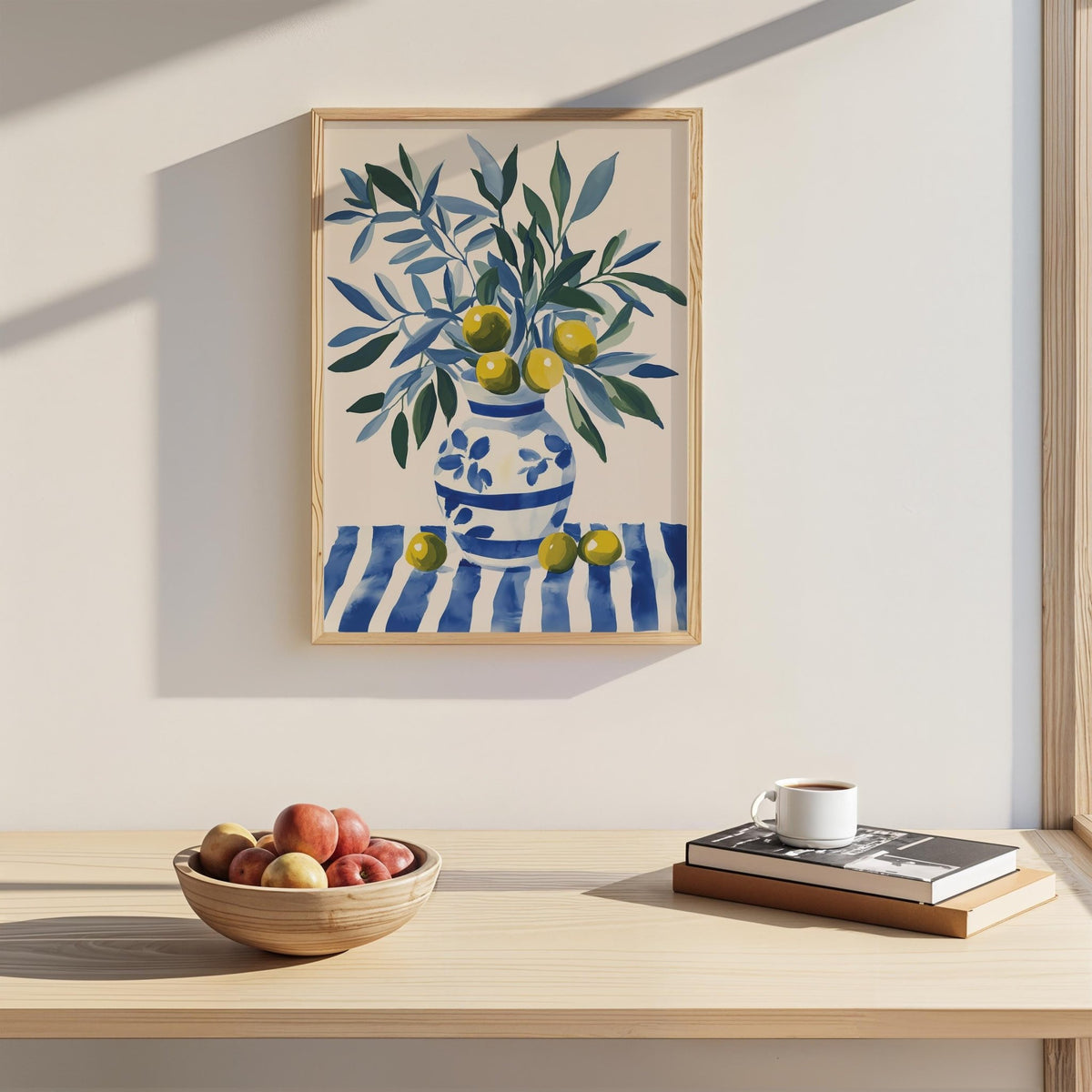 Olive Tree wall art above a light wooden shelf with a fruit bowl and books in natural light