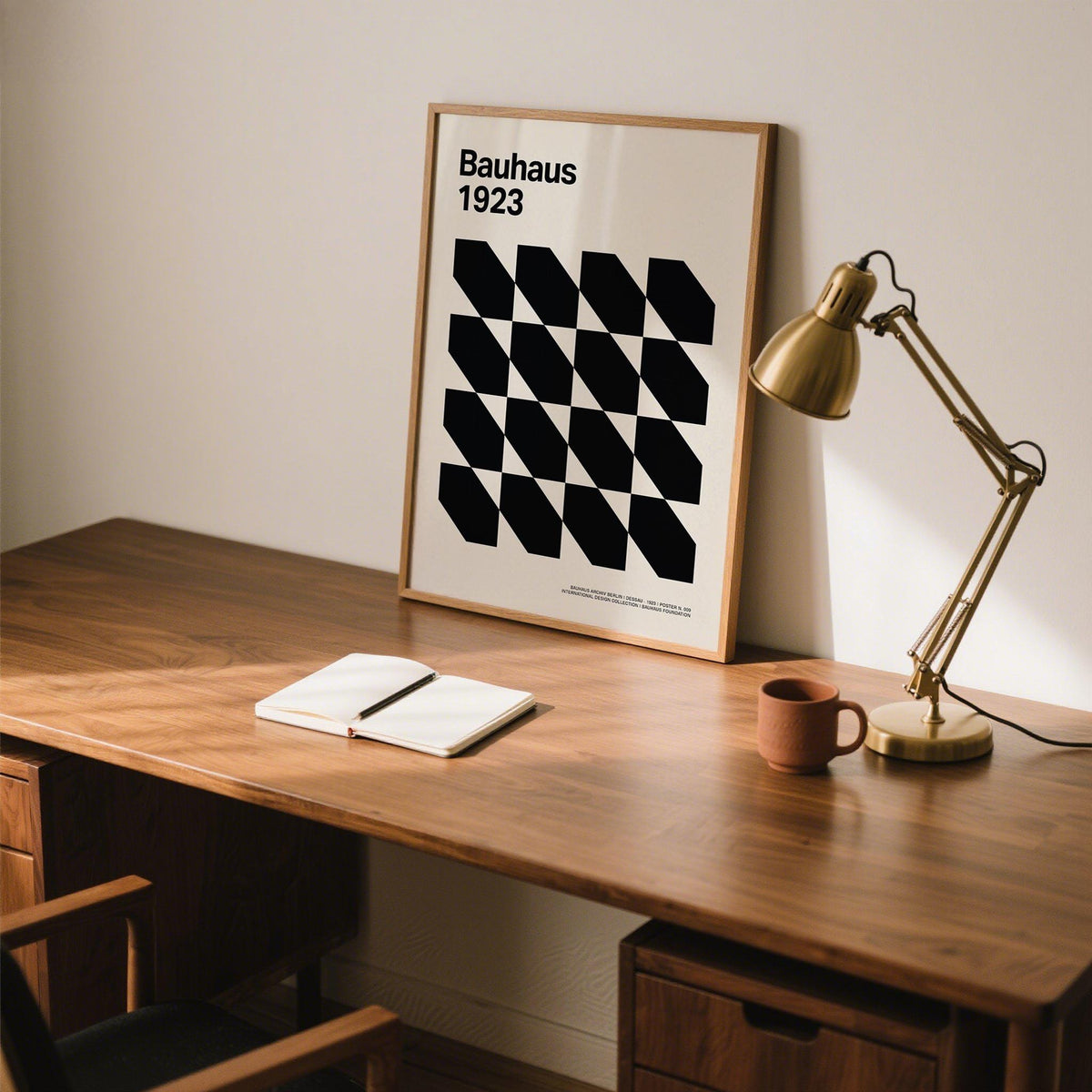 Corporate Office Artwork leaning on a desk with a gold desk lamp and a brown mug