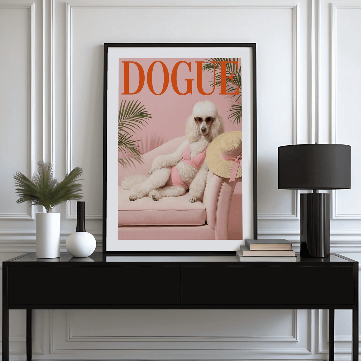 Pink Poodle Print framed print on a console with books and a lamp in a white room