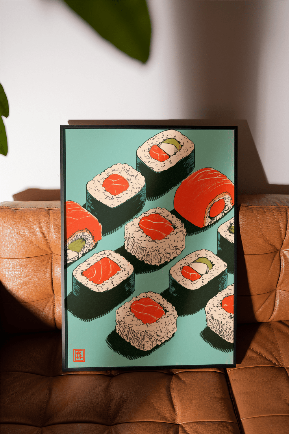 Framed Sushi Art Print with pop-art style sushi rolls and teal background on a brown leather sofa