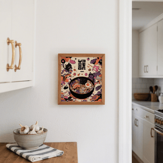 Cat Ramen print framed on a kitchen wall next to white cupboards with a bowl of garlic nearby