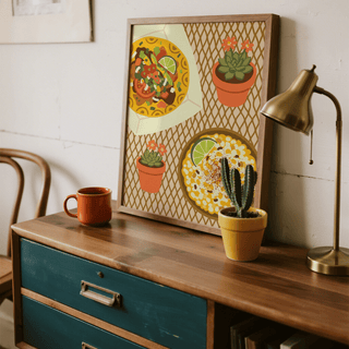 Taco wall art leaning on a wood dresser with a brass lamp and a small cactus