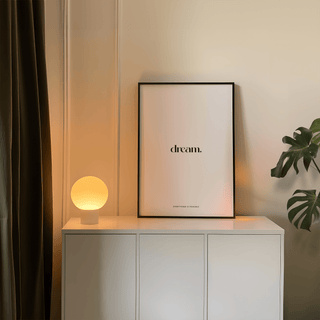Personalised Quote Poster leaning on a white cabinet with a glowing round lamp and a leafy plant nearby
