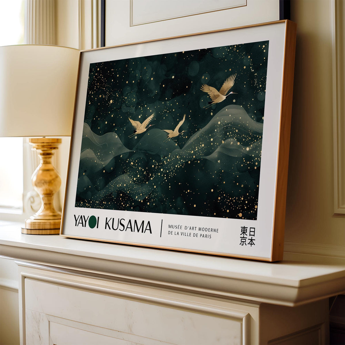 Framed Japanese wall hanging of golden cranes flying over abstract dark green mountains on a mantel