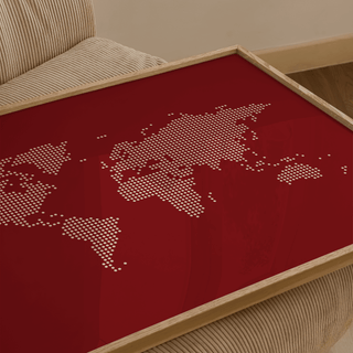 Framed close-up of modern world map wall poster with beige dots on dark red background on a beige corduroy armchair