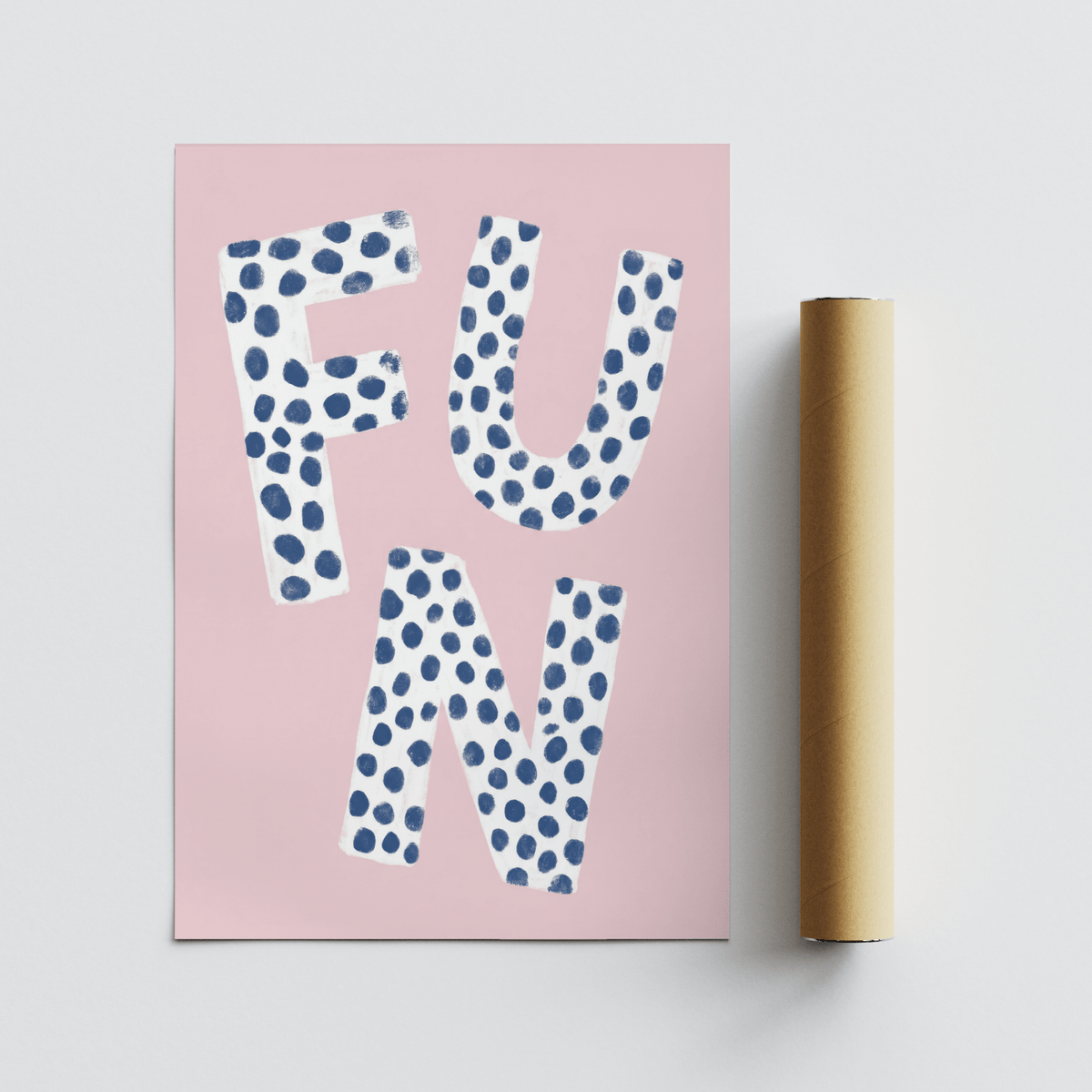 Fun typography wall art with white letters and blue spots on pink background beside a brown packaging tube