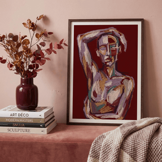 Print leaning on a shelf of a contemporary figure art with abstract human figure in purple and brown shades with a vase nearby