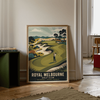 Print leaning on floor of Royal Melbourne Golf Art showing retro style golfer on a green course with trees and hills nearby and a stool