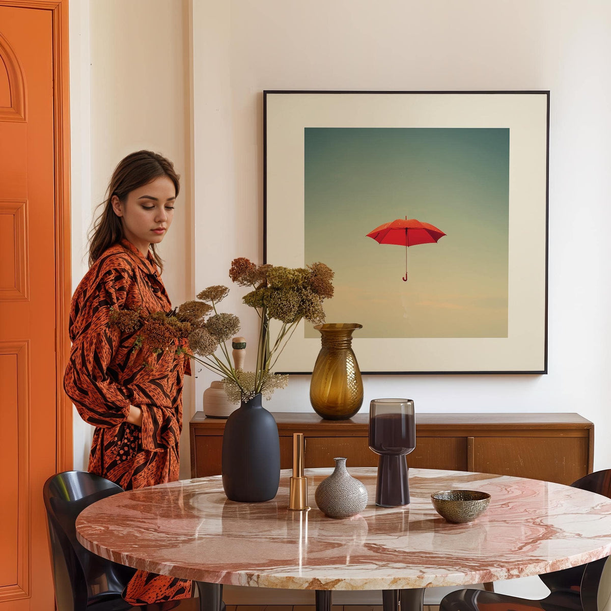 Surreal wall art of a red umbrella floating against a blue sky in a dining room with a marble table