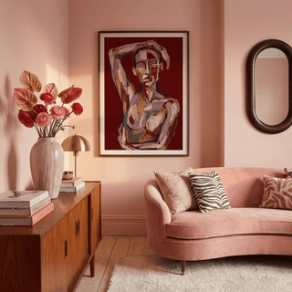 Print on a wall in a pink living room with an abstract human figure in muted reds and browns above a wooden cabinet