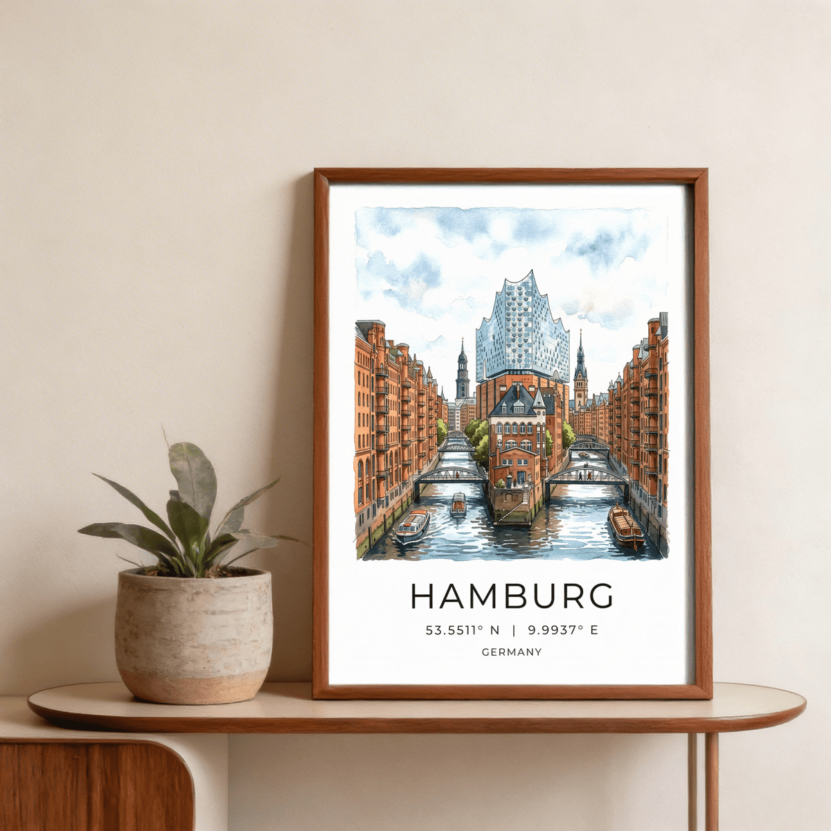 Framed Hamburg Cityscape Art Print watercolour of speicherstadt canal with orange brick buildings and blue sky on a shelf with a green plant